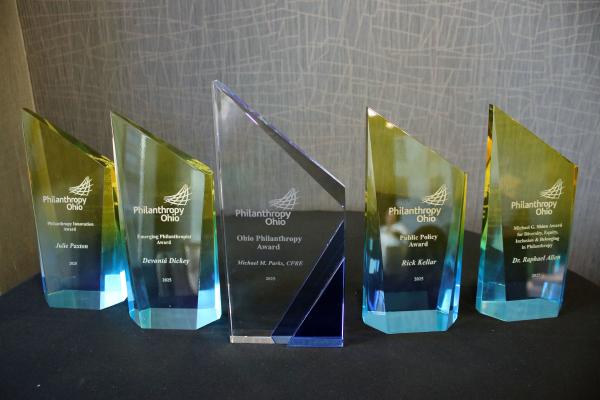 5 glass awards lined up on a table